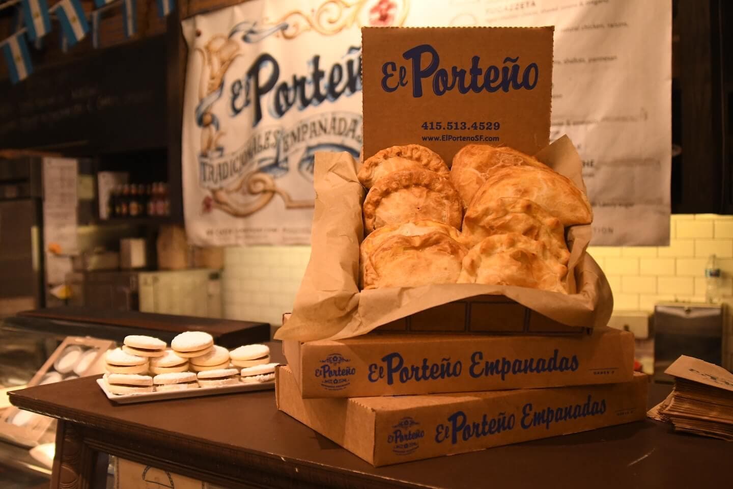 Well-arranged and appetizing boxes of El Porteño empanadas with some pies exposed.